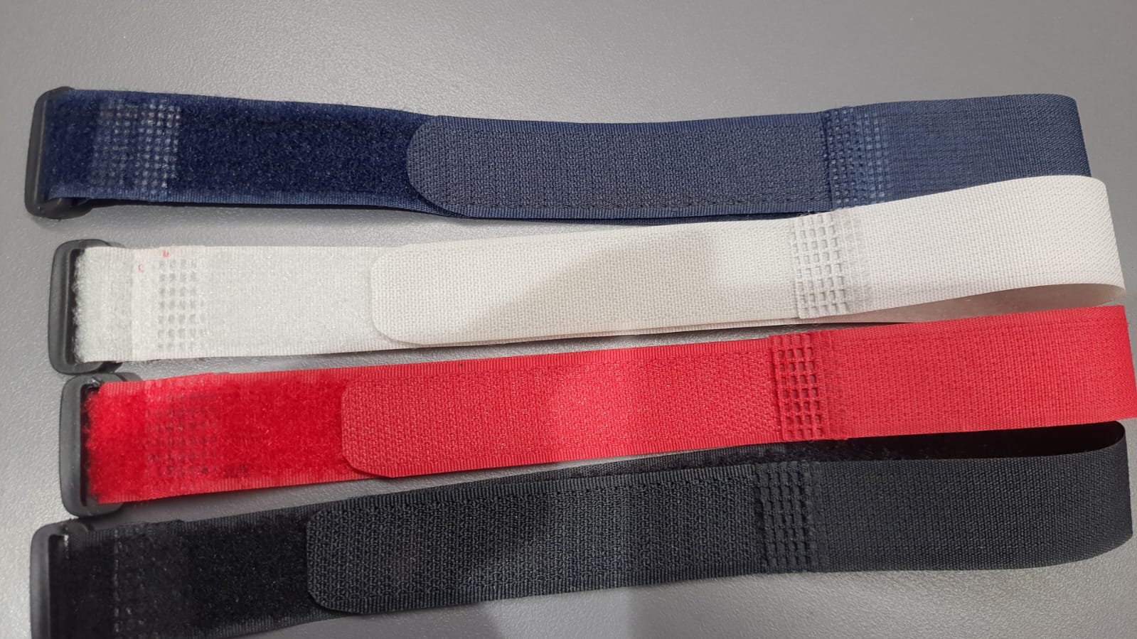 Navy, white, red, and black hook-and-loop cinch straps laid out on a table.